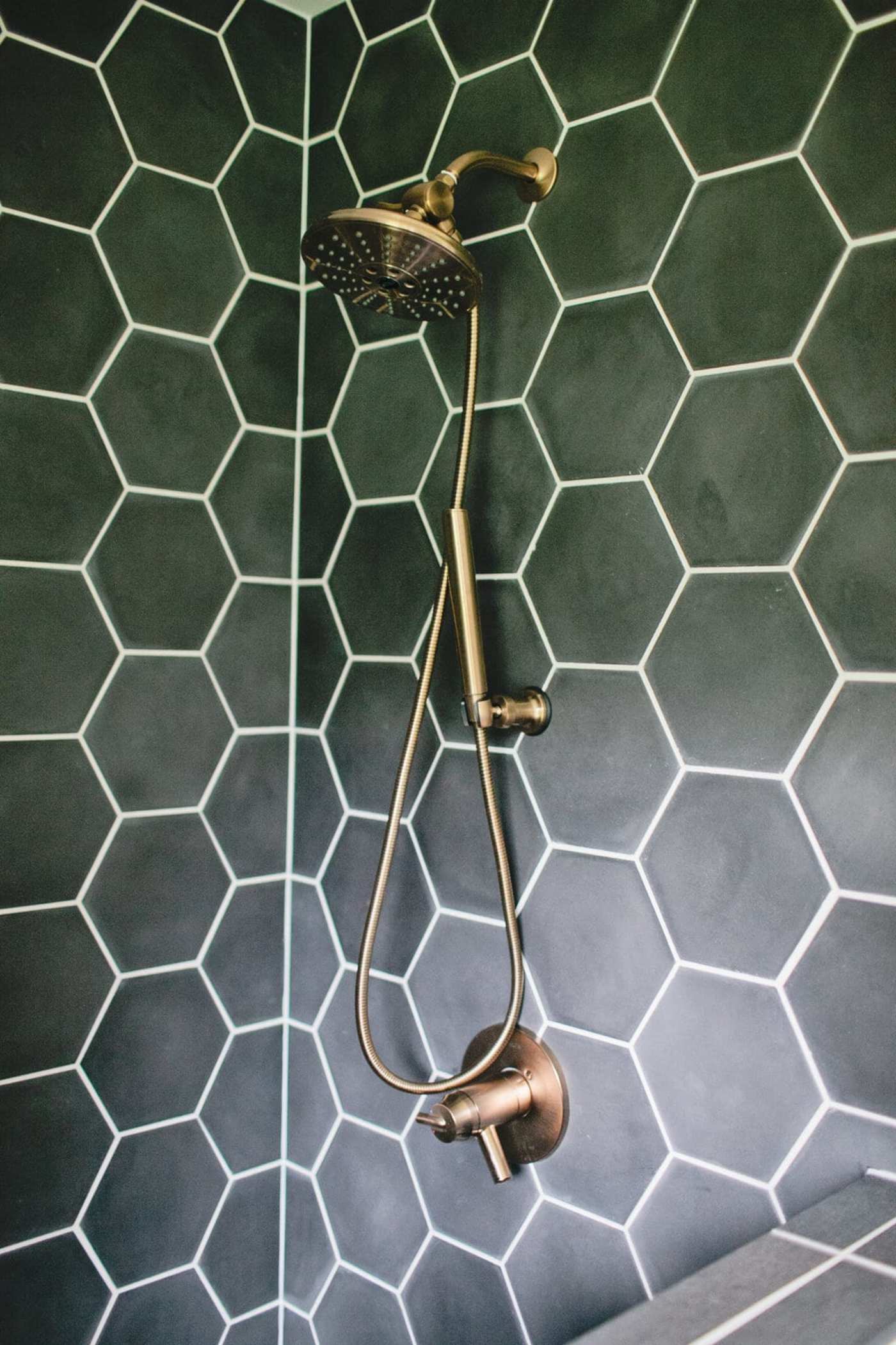 a shower head with a tiled hexagon pattern on the wall.
