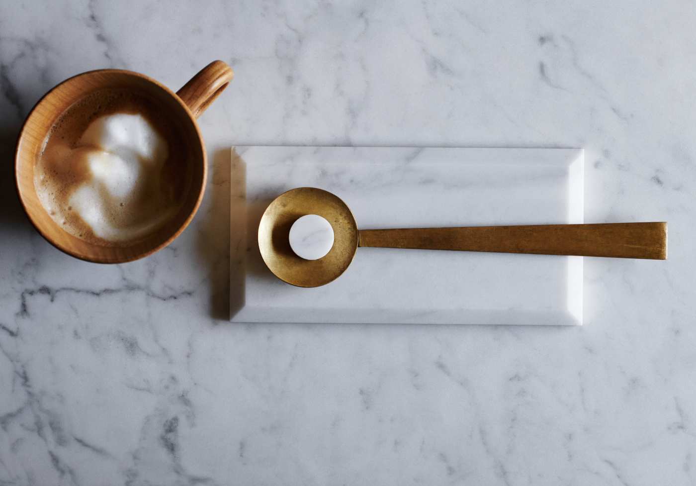 a cup of coffee and a spoon on a marble countertop.