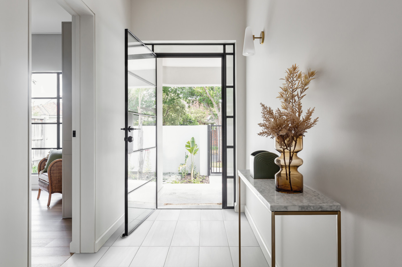 a white hallway with a glass door and a vase.