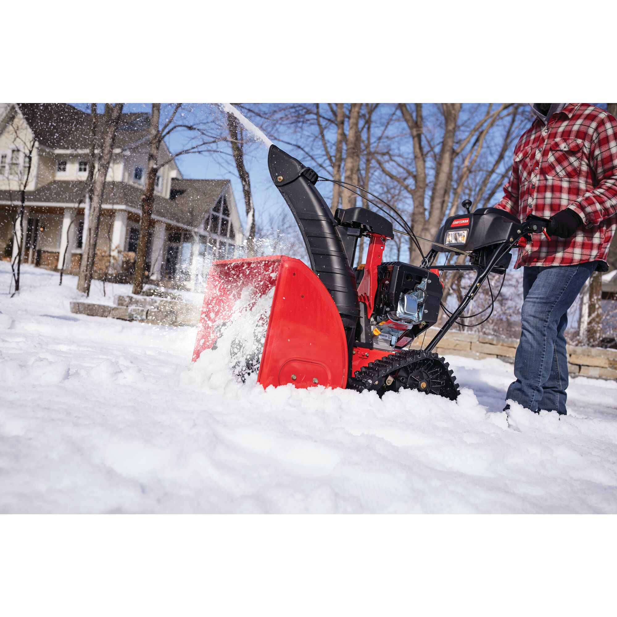 CRAFTSMAN 208CC Electric Start Track Drive Snow Blower blowing snow in front of a house in side view in plaid shirt 