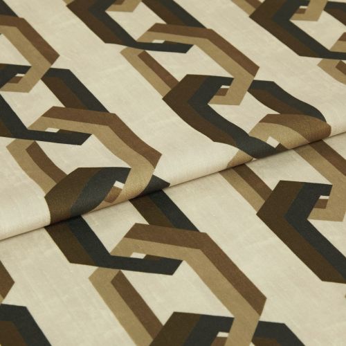 Cream fabric sample printed with repeating brown and black interlocking geometric shapes; folded across the center; close-up studio shot with soft, even lighting on a neutral background.
