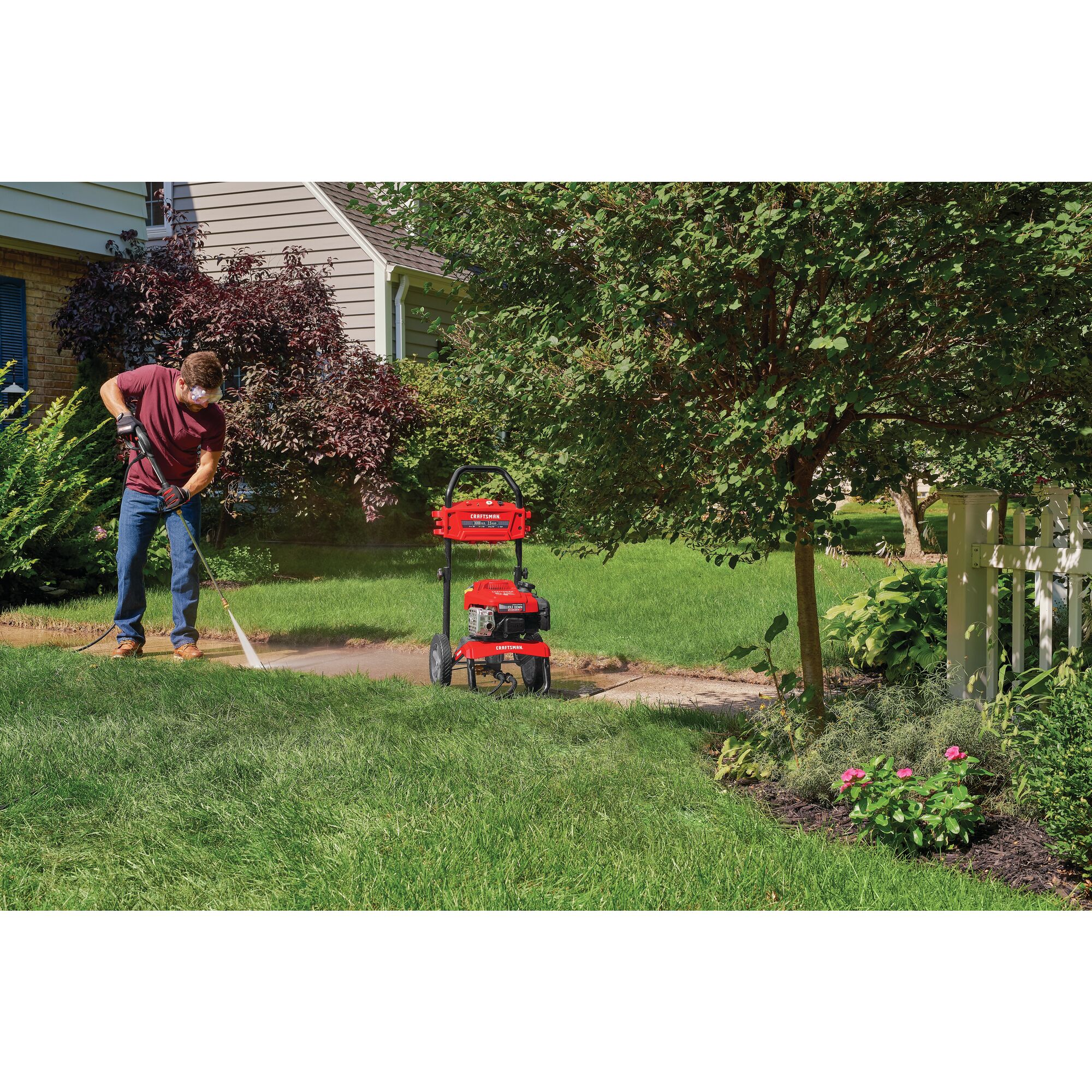 3000 MAX Pounds per Square Inch or 2 and five tenths MAX Gallons Per Minute Pressure Washer being used by person to wash pathway in lawn outdoors.