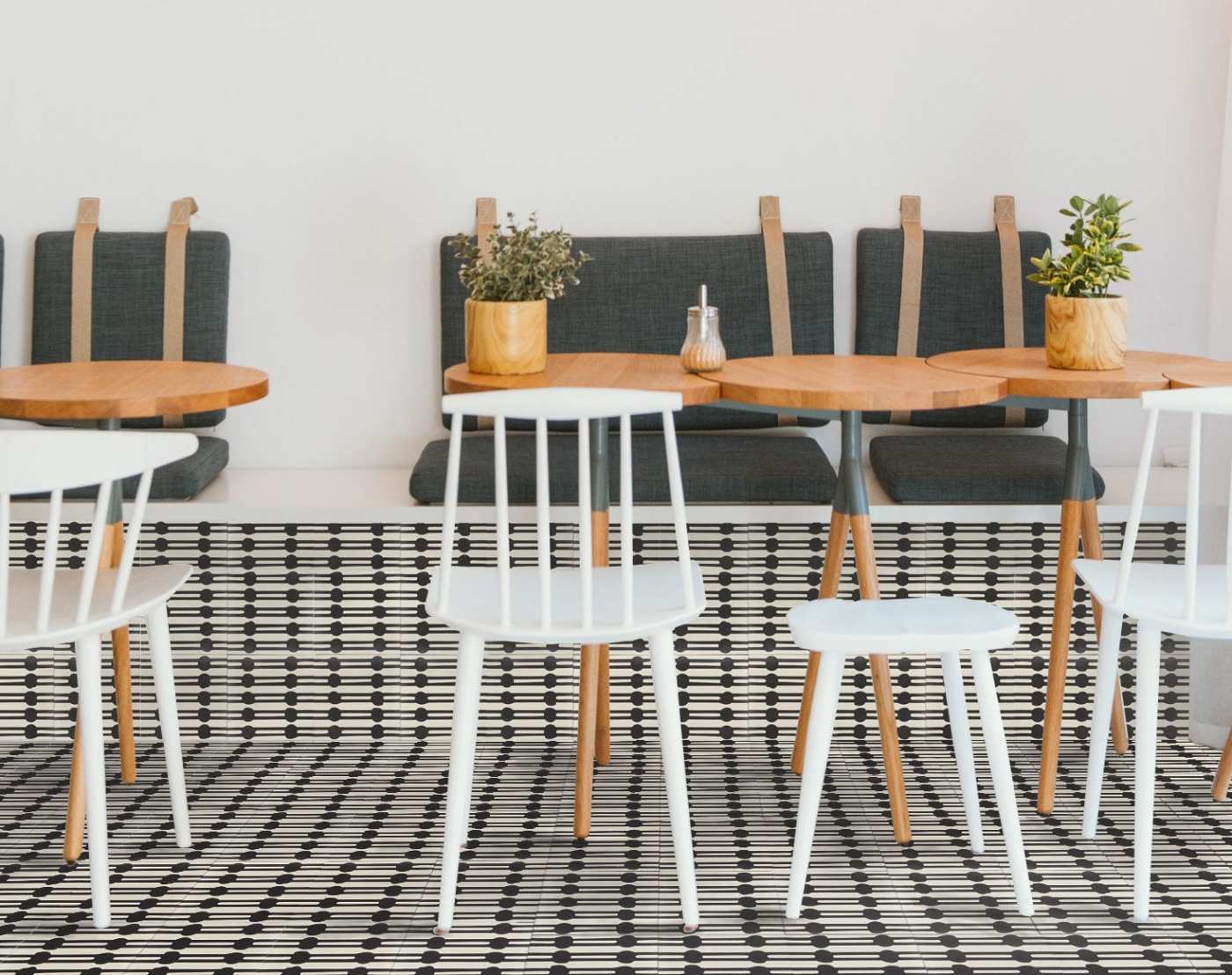 a cafe with white chairs and a black and white tiled floor.