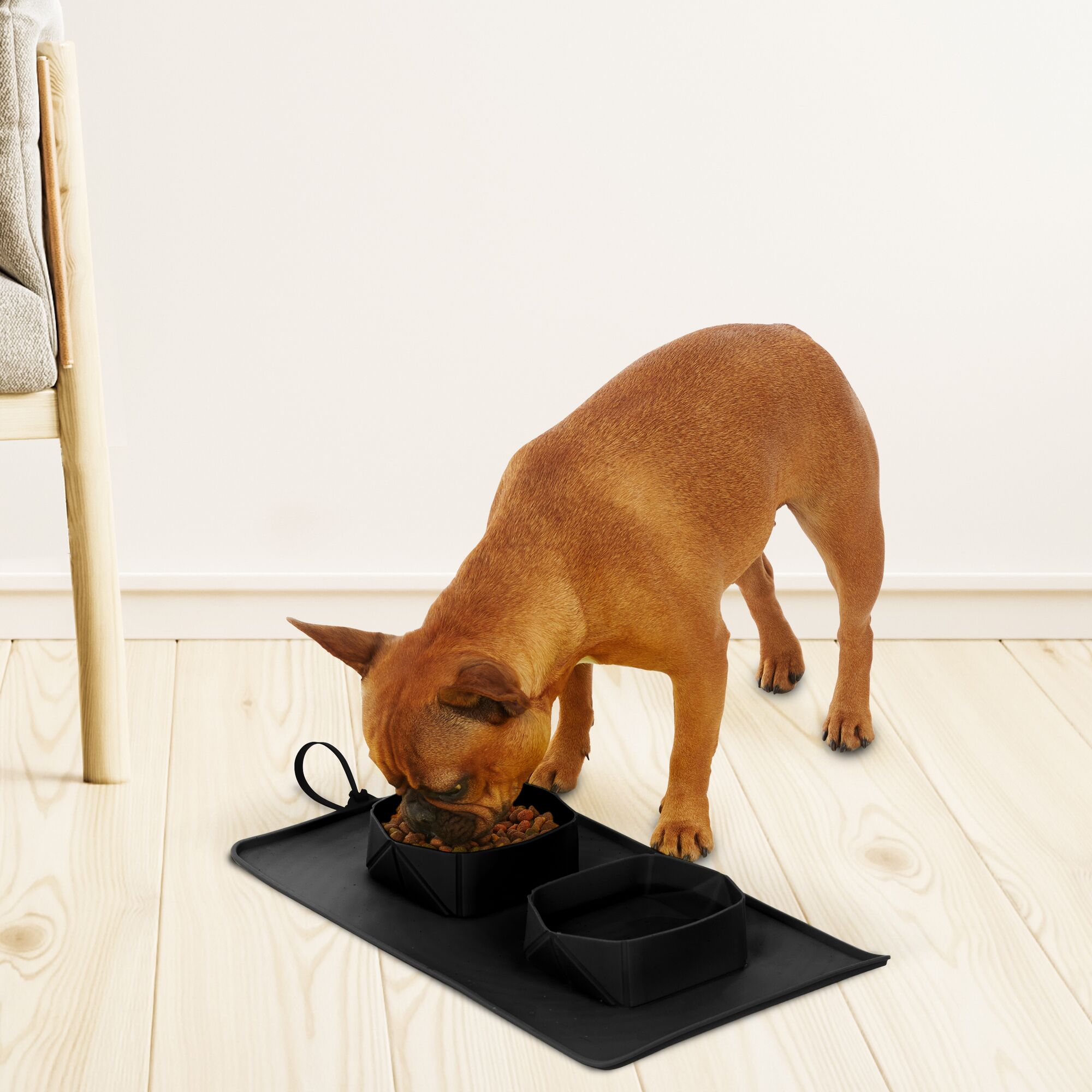 Brown Frenchie eating from black Double Diner Black and Decker Silicone Travel Mat next to chair