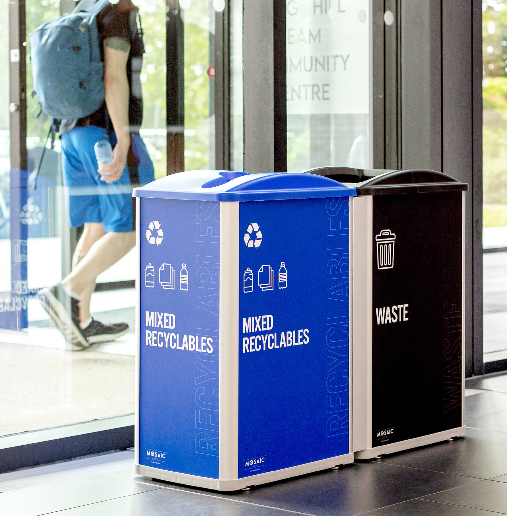 a mixed recyclables and waste station with large body signs sitting inside a recreation facility
