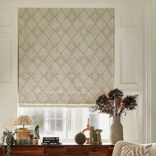 Beige fabric Roman blind with stitched diamond pattern, lowered to cover the window and softly filtering daylight. Beside a wooden console with lamp, books and a vase of dried flowers.
HOMES FOR OUR TIME
EVERYTHING ABIGAIL AHERN