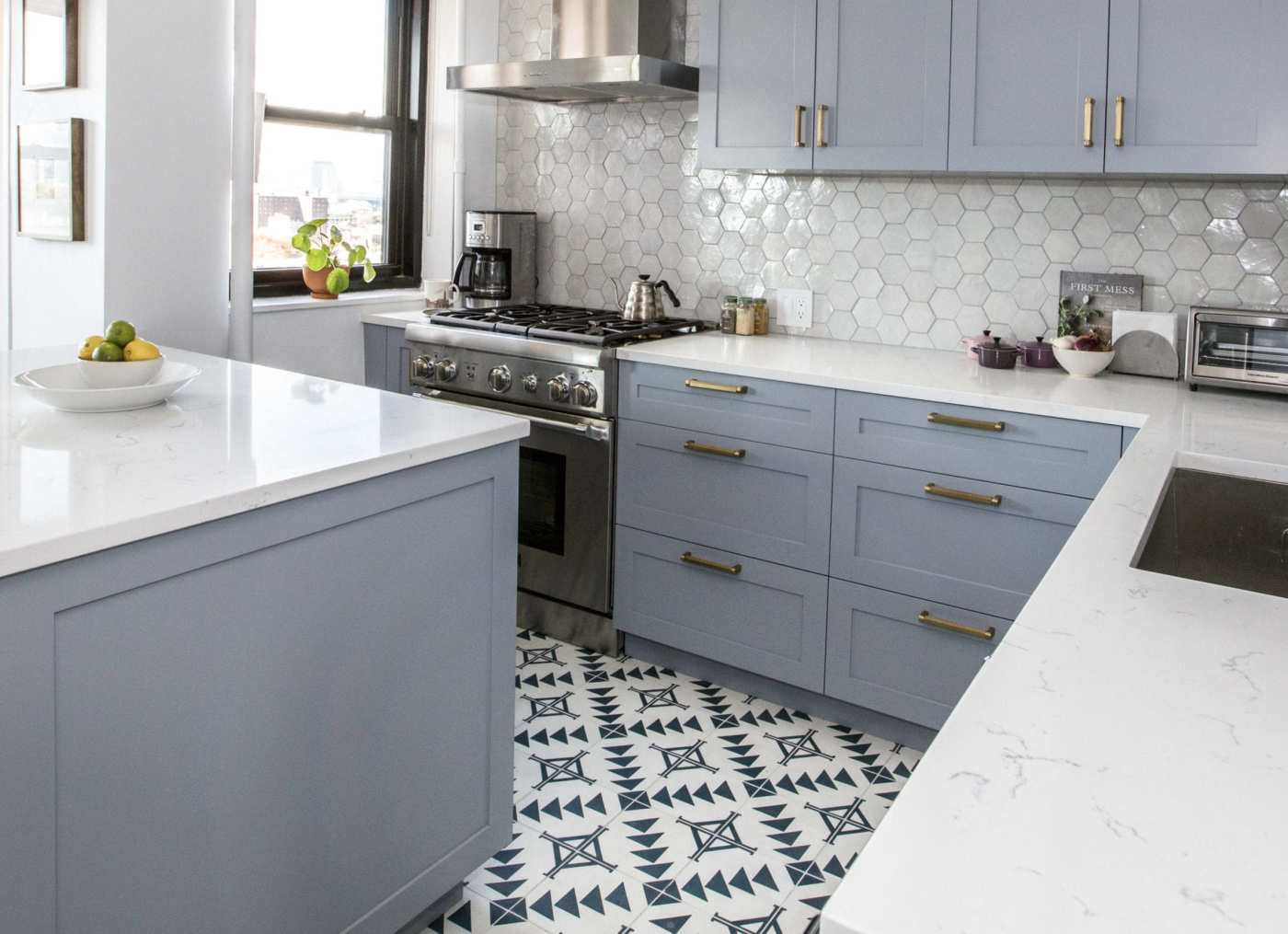 a kitchen with grey cabinets and a black and white tile floor.