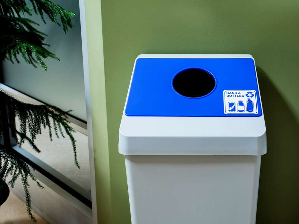 grey plastic cans and bottles recycling container with a blue circle opening lid in a corporate office environment