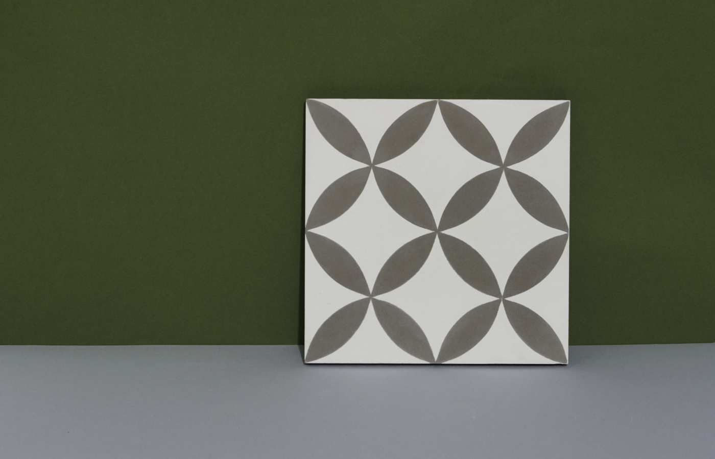 a white and grey tile on a green background.