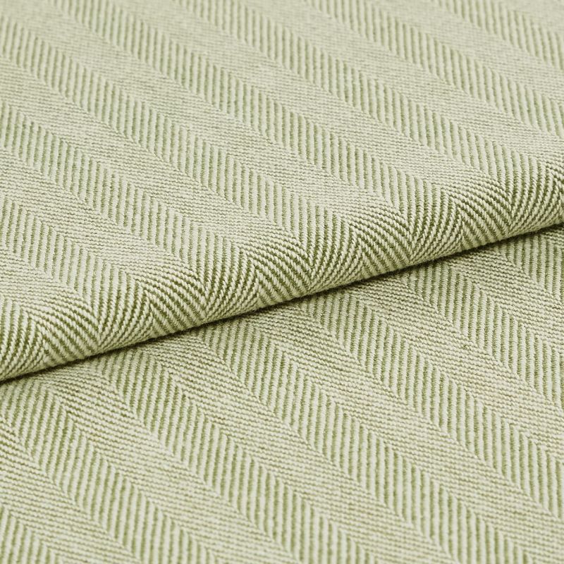 Pale green woven fabric with raised diagonal ribbed herringbone pattern, folded across the frame; the fabric displays pronounced texture and ridges under soft, even studio lighting in a close-up view.
