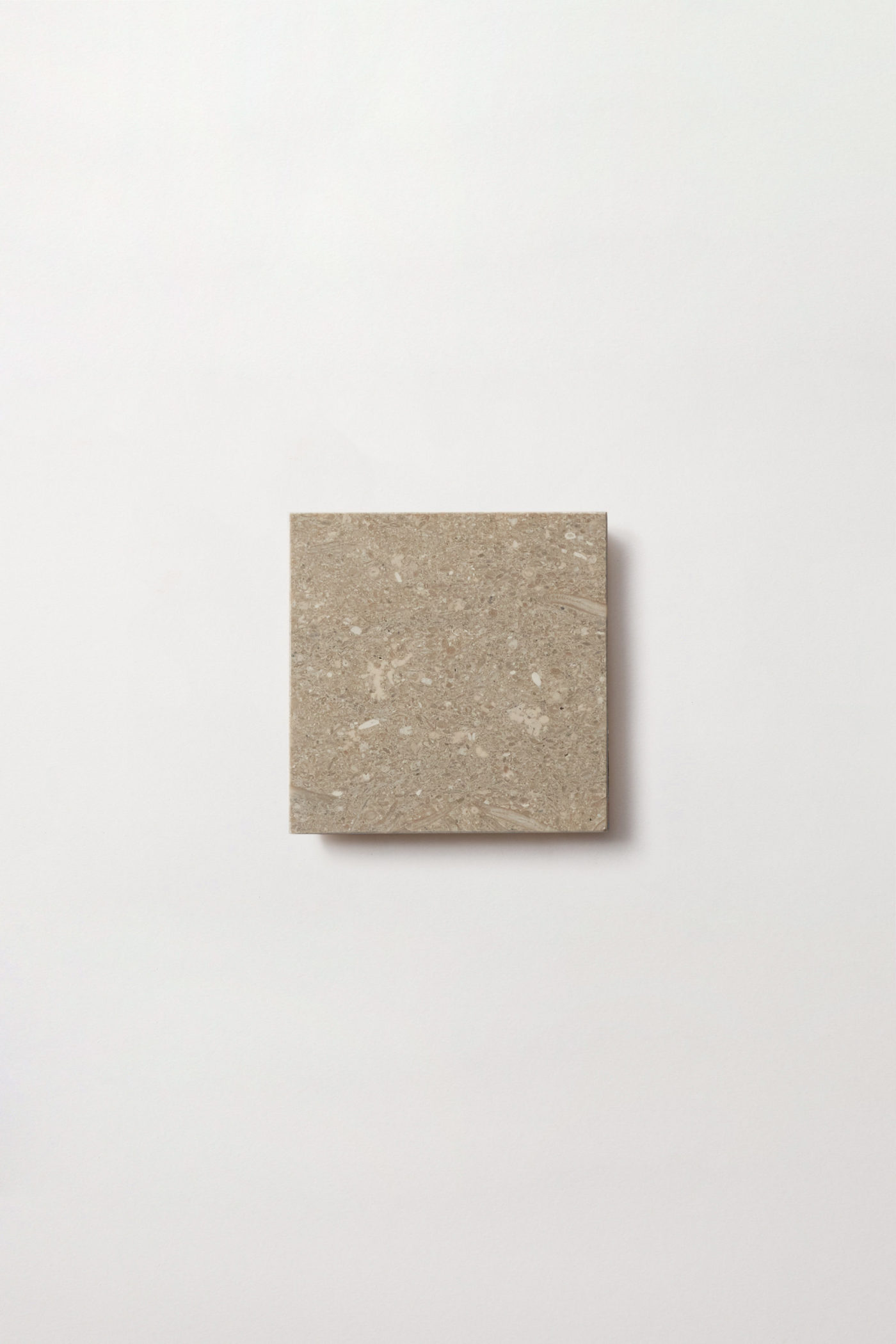 a square beige tile on a white surface.