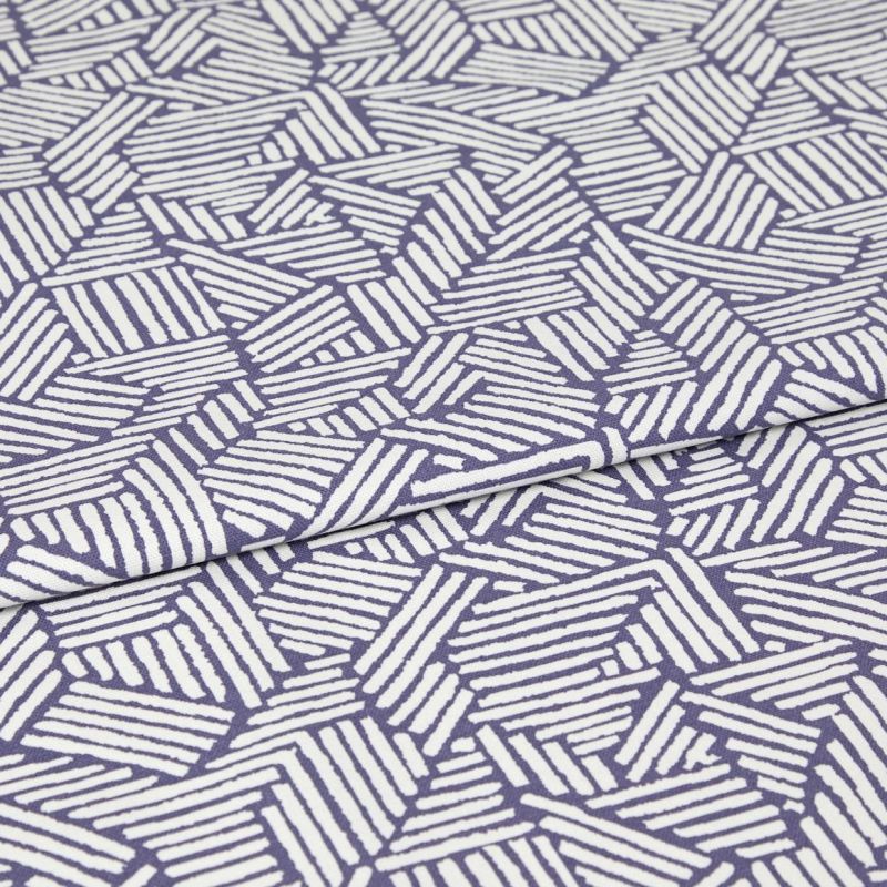 Folded fabric with purple background and white hand-drawn diagonal stripe hexagon pattern; the cloth is folded once with a visible overlap; close-up on a flat surface under even studio lighting.
