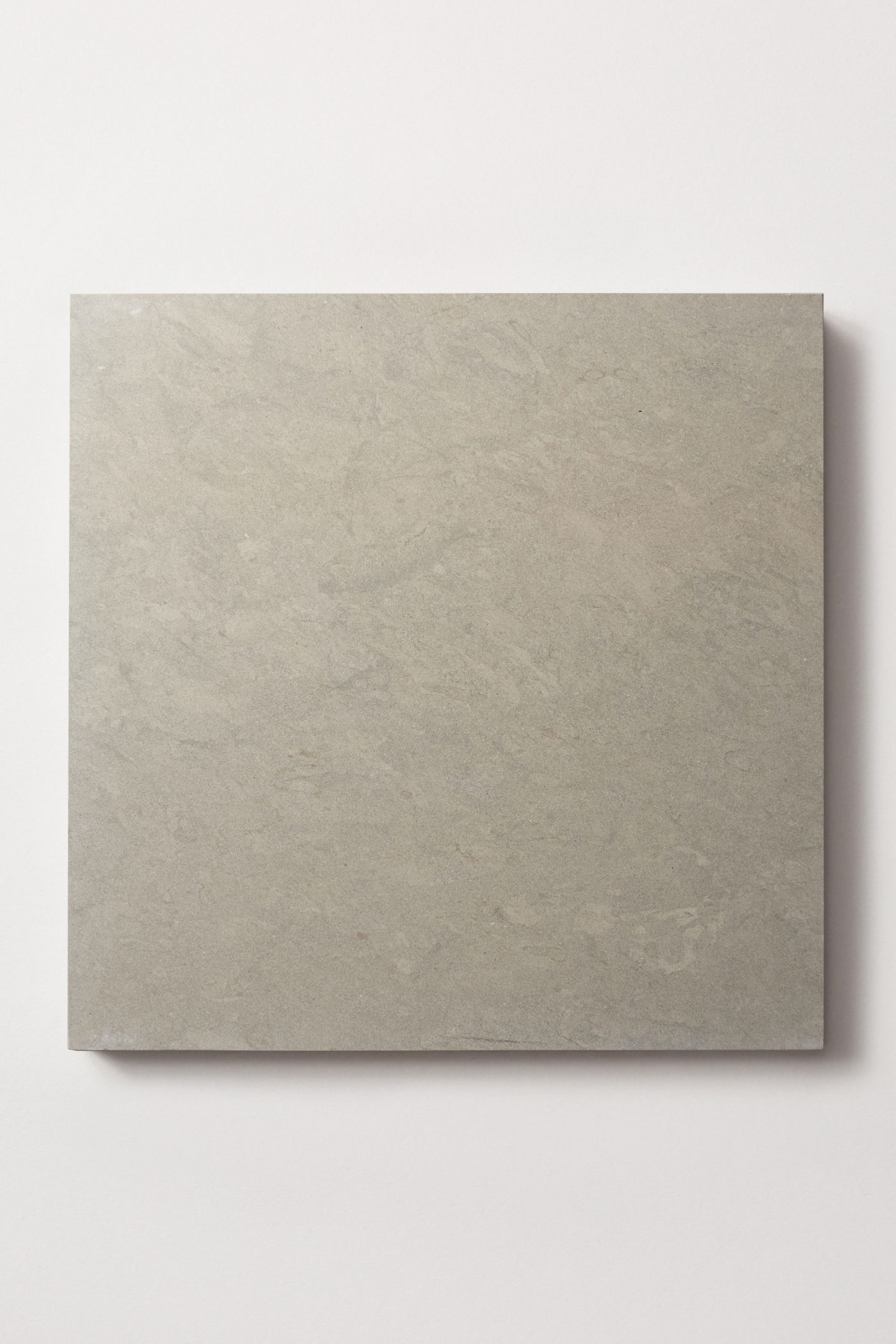 a square grey limestone tile on a white surface.