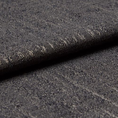 Dark gray woven fabric with slubs and subtle metallic threads; folded into a layered edge; tight macro close-up on a softly lit surface, neutral background suggesting an upholstery sample.