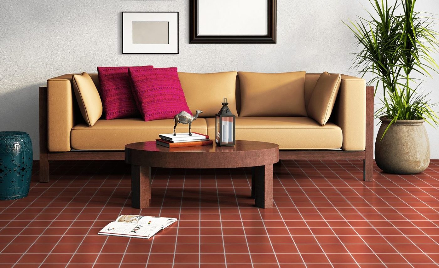 a living room with a red tile floor, a couch, and a plant.