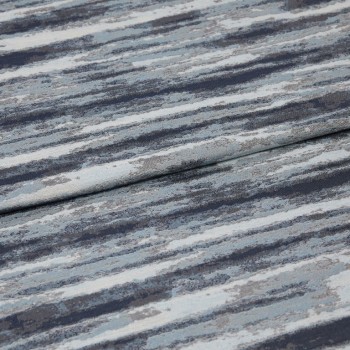 Folded jacquard curtain fabric with horizontal blue-gray, navy, and white striations; draped over itself, revealing woven texture and subtle sheen in a close-up, softly lit studio view.