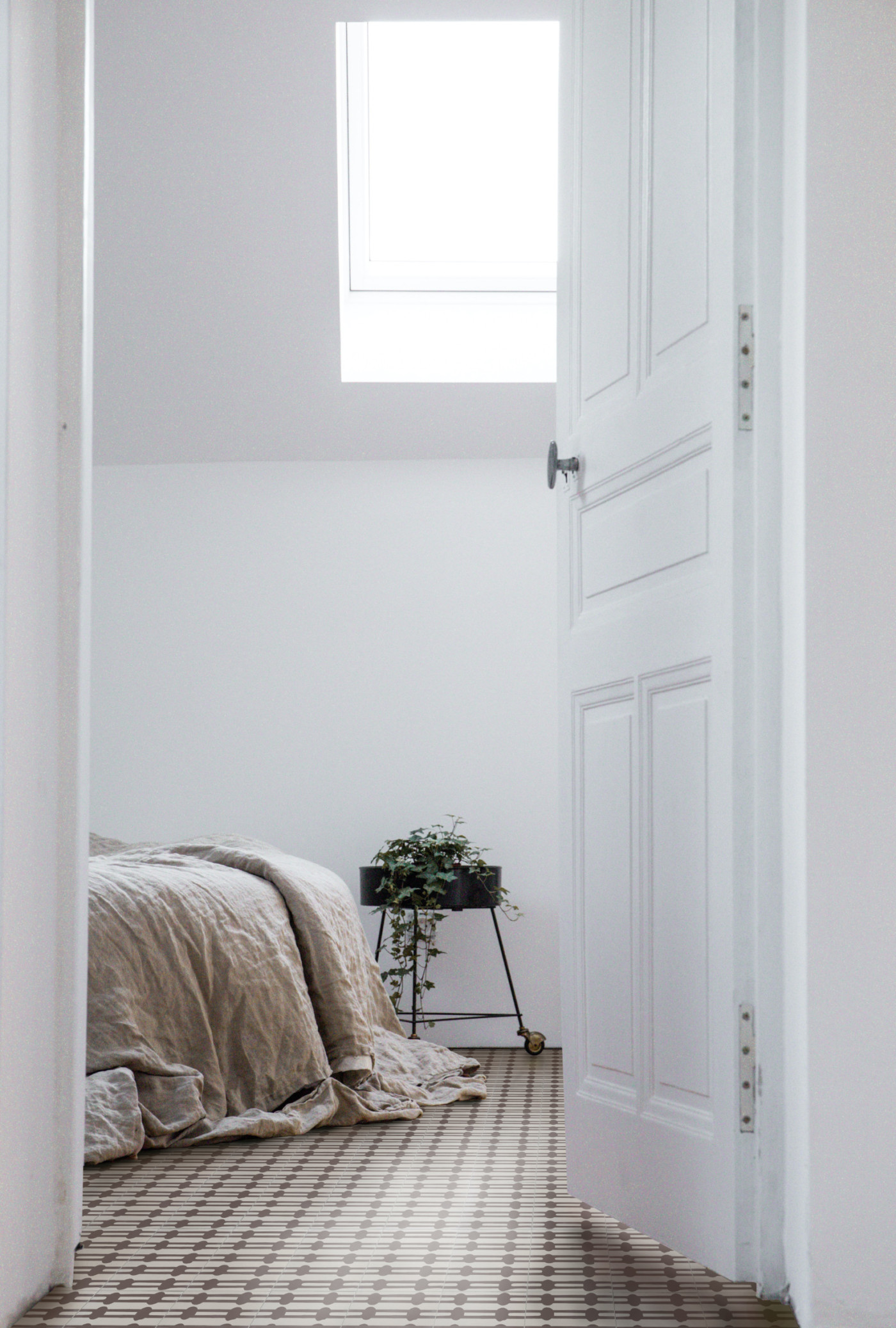 an open door leading to a bedroom with a bed and a window.