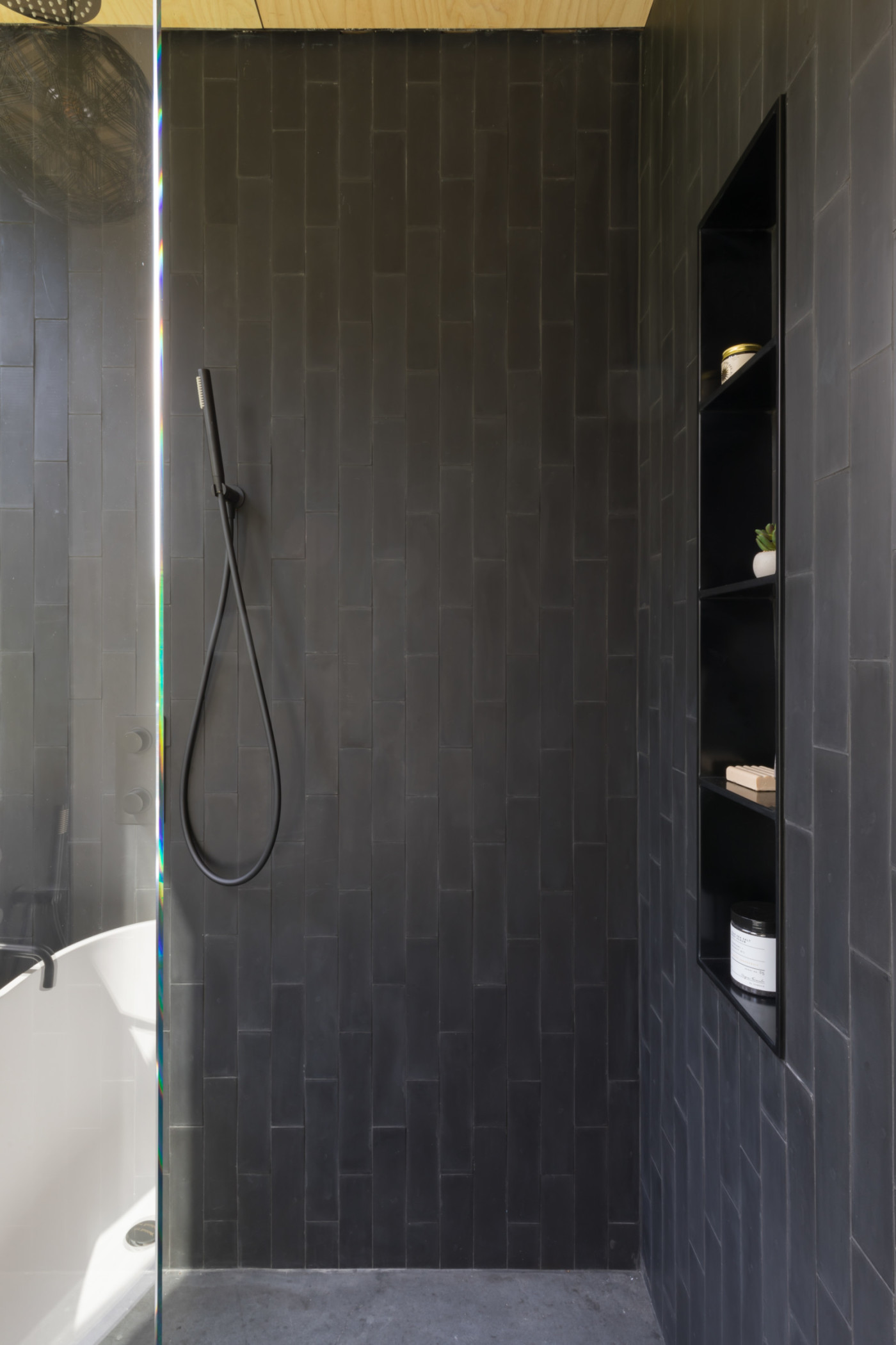 a black tiled shower with a glass door.