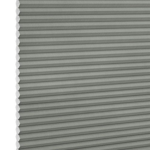 Cellular honeycomb blind, light gray with visible hexagonal cell ends at the left edge; closed and fully lowered into tight horizontal pleats; interior setting with soft diffuse lighting, no visible view.