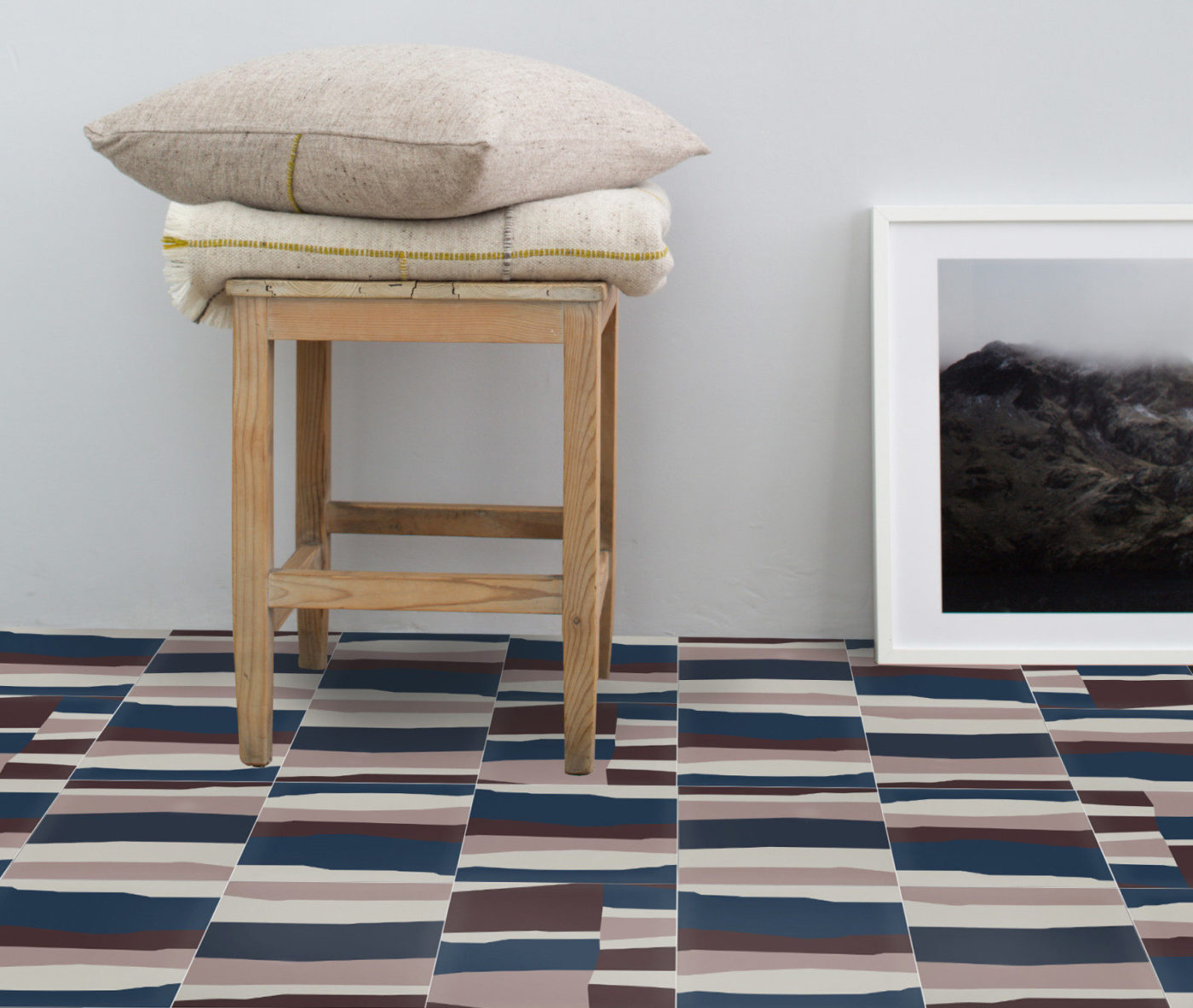 a room with a stool, a framed picture, and colorful floor tiles.