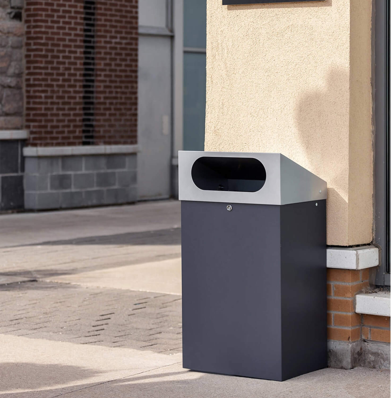 durable powder coated steel outdoor trash bin with locking lid and large waste opening outside a shopping plaza