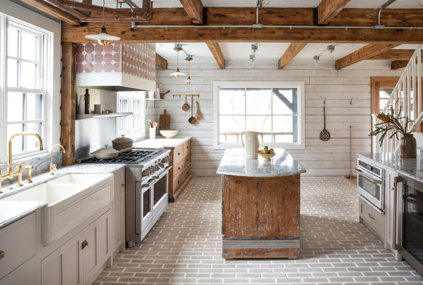 a white kitchen with wood beams and a large island.
