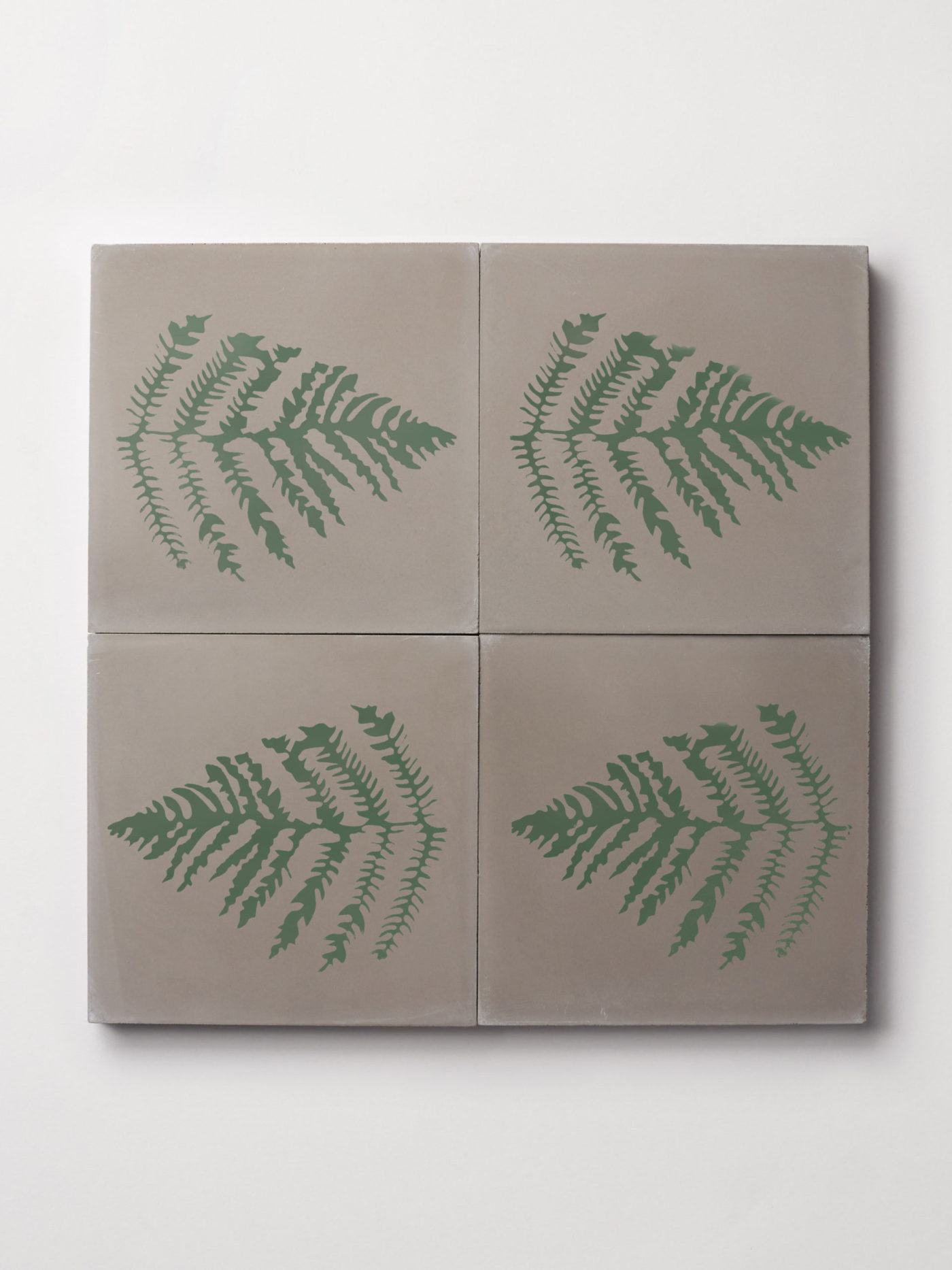 four grey tiles with designs of fern leaves on them.