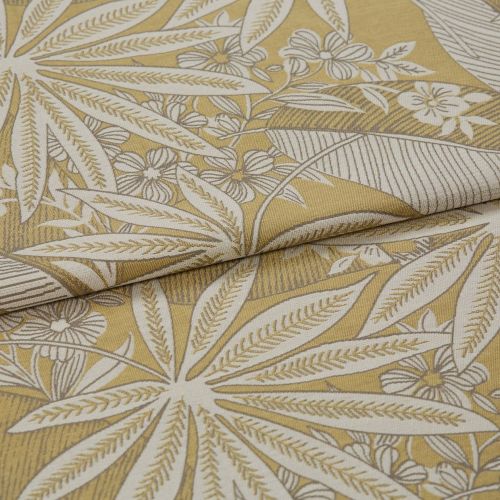 Botanical-patterned upholstery fabric, folded to show a layered edge; cream leaf-and-flower woven motif on mustard-yellow background, close-up studio shot with soft even lighting.