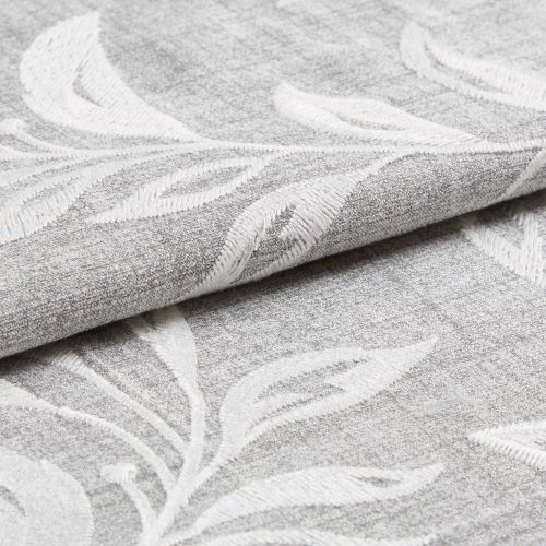 Textured gray fabric with raised white leaf embroidery folded and partially rolled, overlapping; close-up studio-lit view highlighting the weave and embossed botanical pattern.