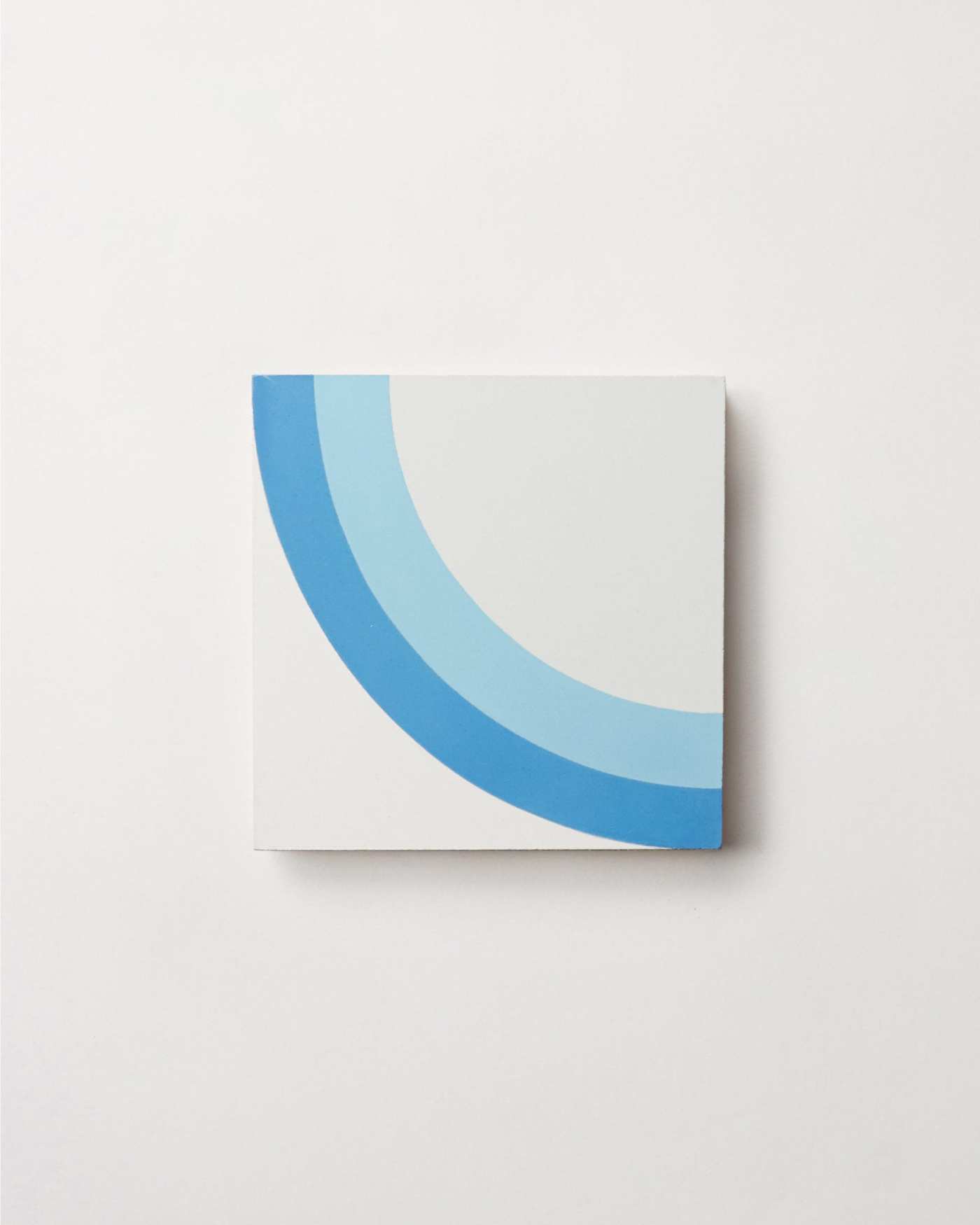 a white tile with a blue and white abstract design on a white surface.