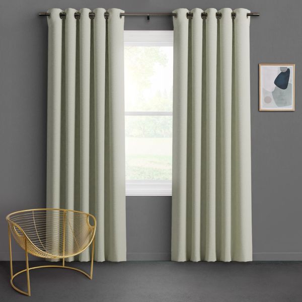 Grommet-top pale sage curtains, floor-length with deep pleats, hung on a metal rod and parted slightly, filtering soft daylight over a gray-walled room with gold wire chair and abstract art.