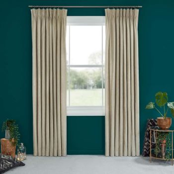 Beige pinch-pleat curtains on a metal rod, drawn to either side, framing and partially revealing a sunlit white-framed window; teal living-room wall, carpeted floor, plants and a side table.
