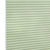 Pale green honeycomb (cellular) blind with visible hexagonal cells at left, fully lowered and closed, softly filtering light; studio-lit product shot on a white background.