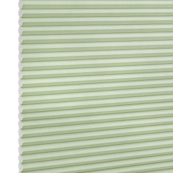 Pale green honeycomb (cellular) blind with visible hexagonal cells at left, fully lowered and closed, softly filtering light; studio-lit product shot on a white background.