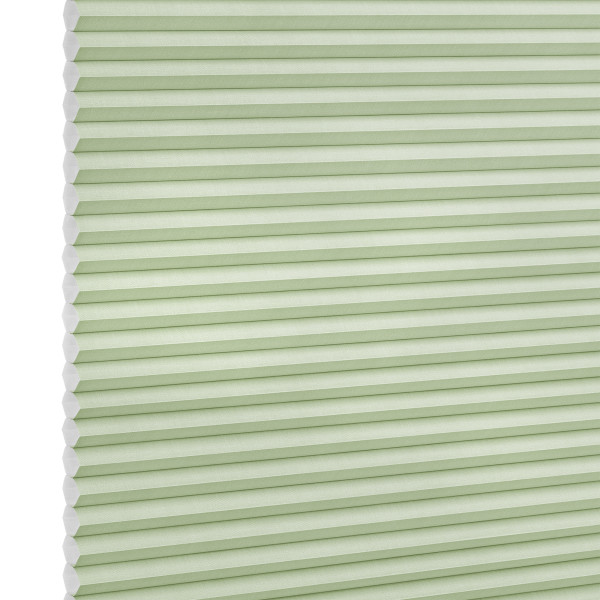 Pale green honeycomb (cellular) blind with visible hexagonal cells at left, fully lowered and closed, softly filtering light; studio-lit product shot on a white background.