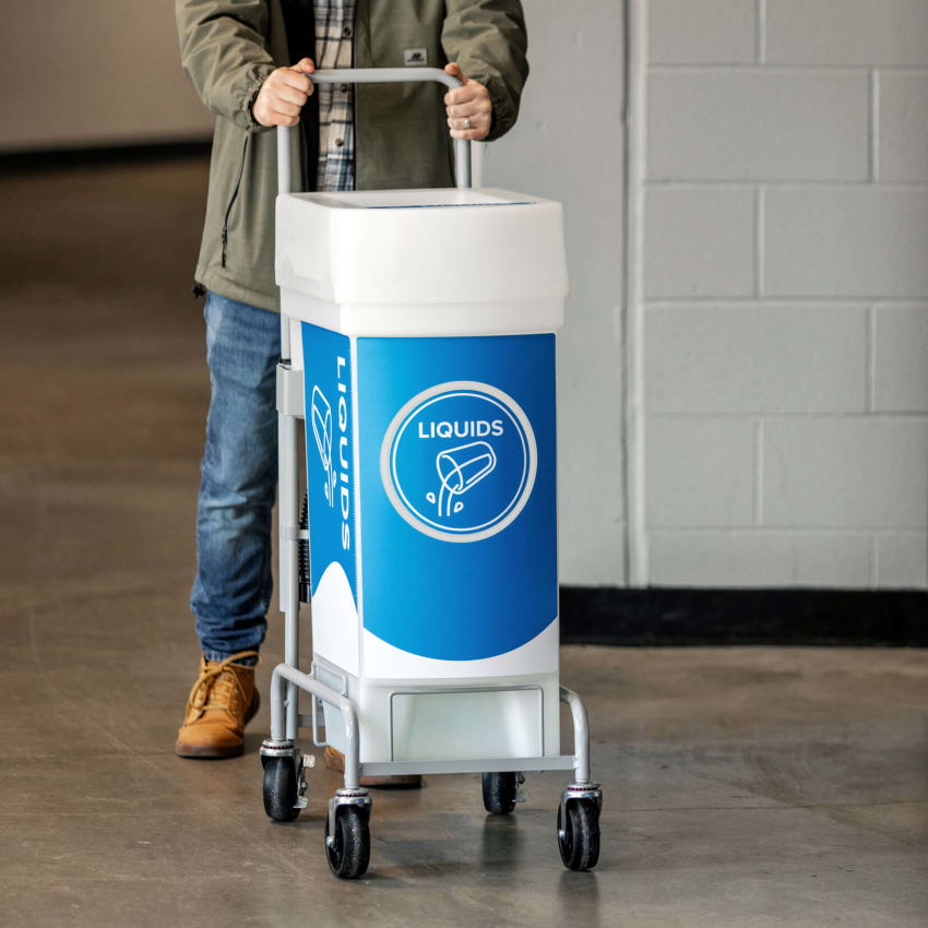custodian pushing liquid waste collection bin down hallway in a stadium
