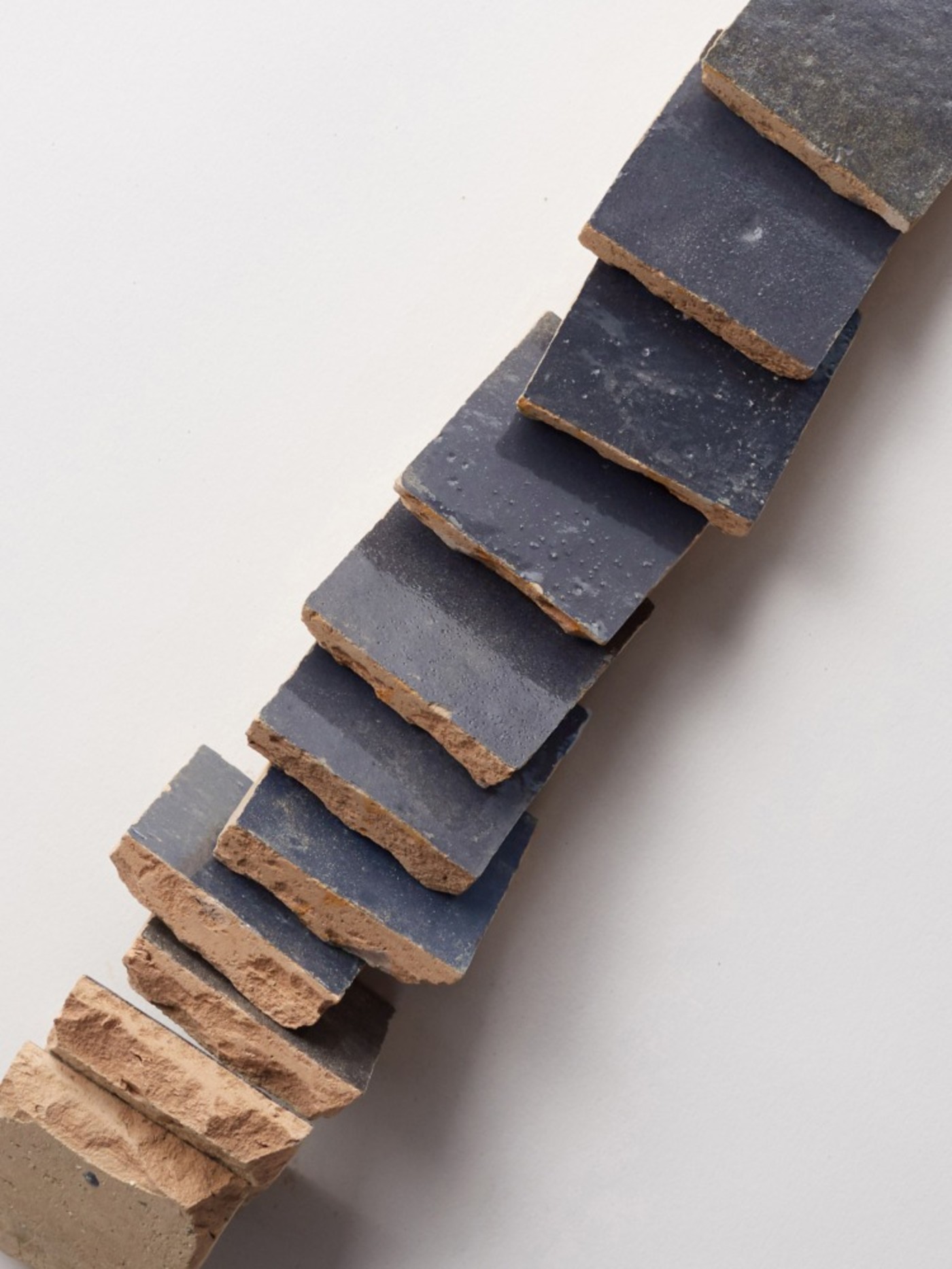 a stack of dark tiles on a white surface.