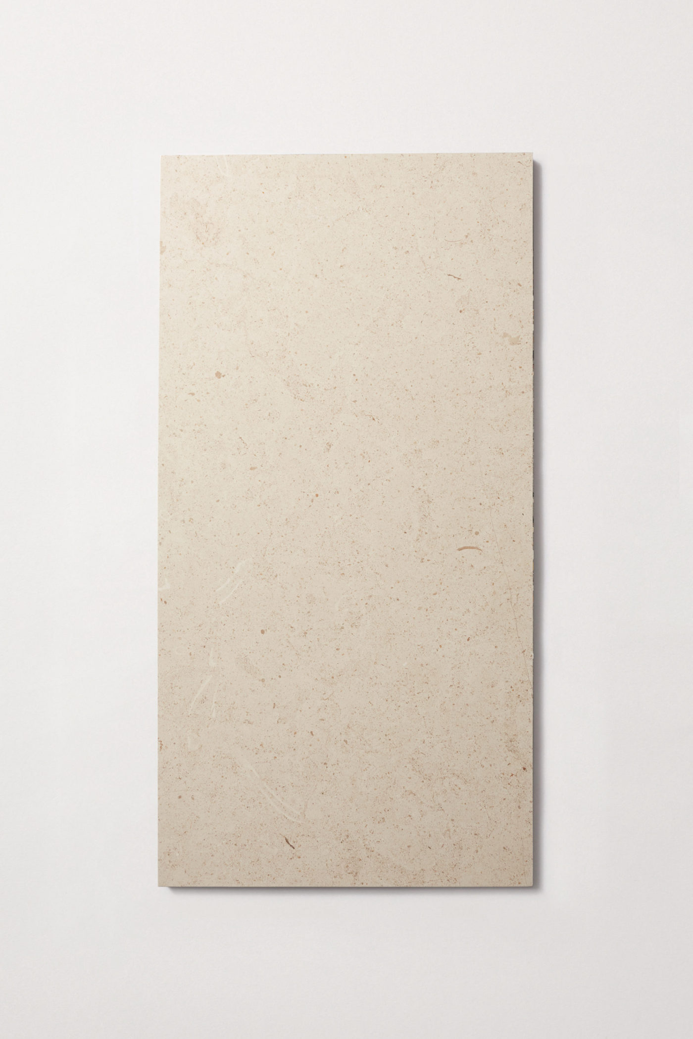 a rectangular beige limestone tile on a white surface.