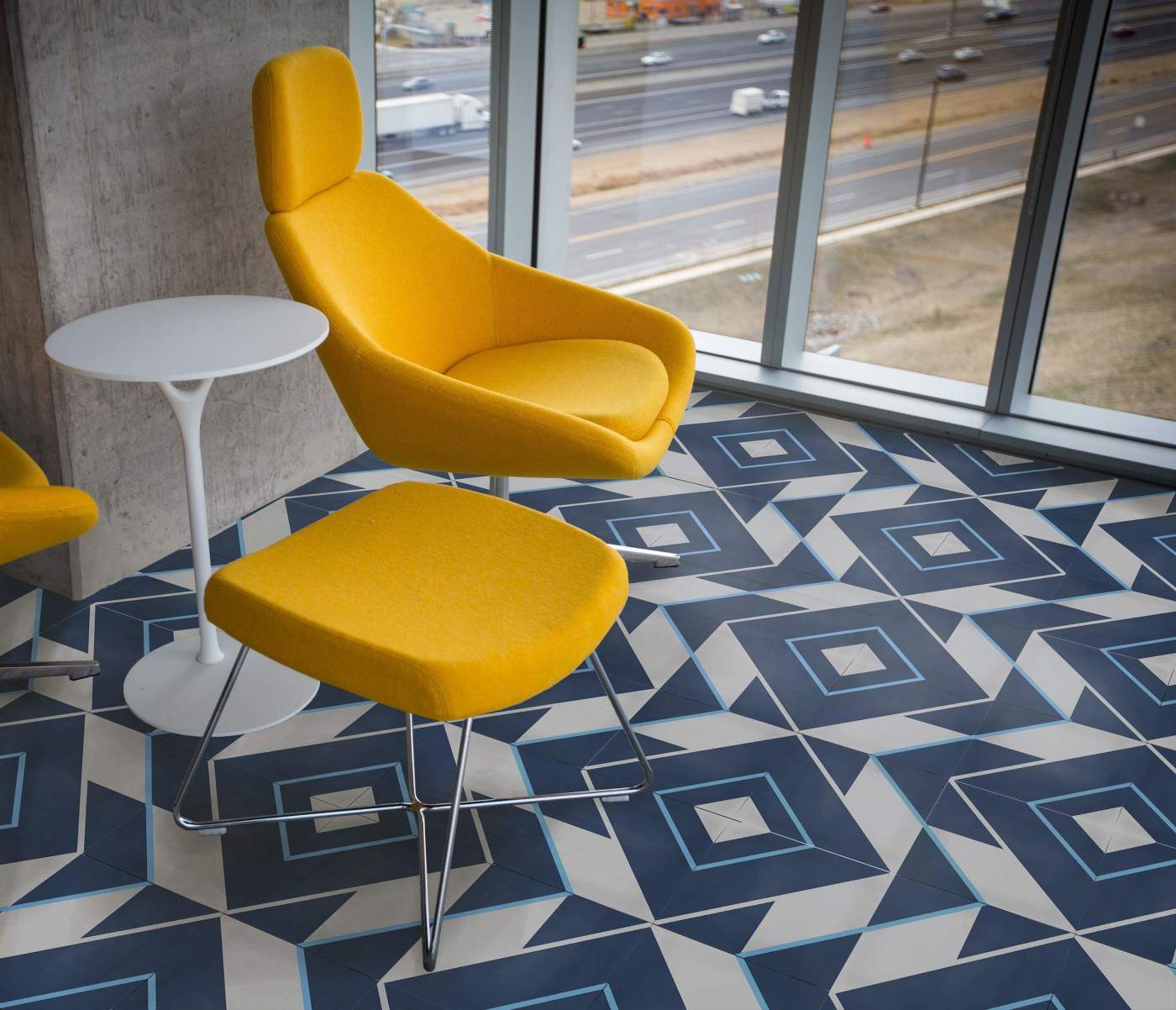 a yellow chair and a white table in a blue tiled room with a view.