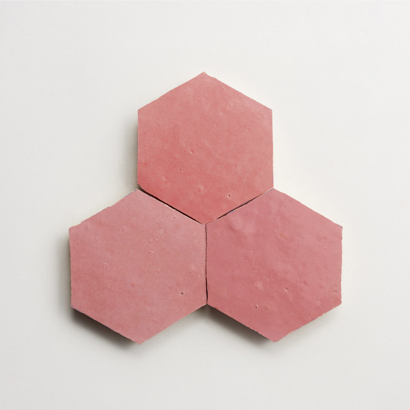 three pink hexagon tiles on a white surface.