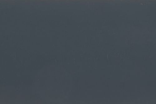 Dark gray-blue matte surface filling the frame, with faint vertical scratches; unadorned and featureless, low ambient light, ambiguous interior or exterior setting.