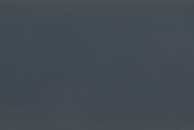 Dark gray-blue matte surface filling the frame, with faint vertical scratches; unadorned and featureless, low ambient light, ambiguous interior or exterior setting.