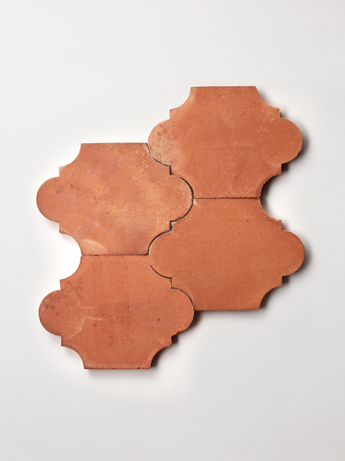 four red, ornamental terracotta tiles on a white background.