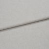 Light gray linen-like fabric folded horizontally, creating a soft crease; close-up shows fine woven texture under even neutral lighting, appearing as a fabric sample or upholstery material on a flat surface.