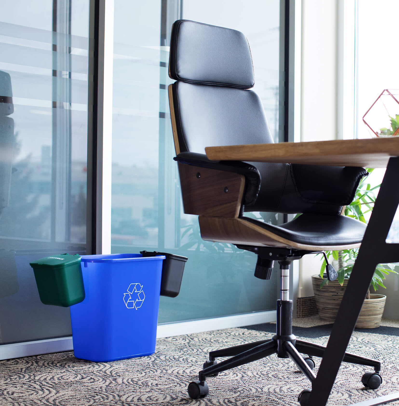 green hanging organics and waste bins on the side of a blue recycling container in a modern office