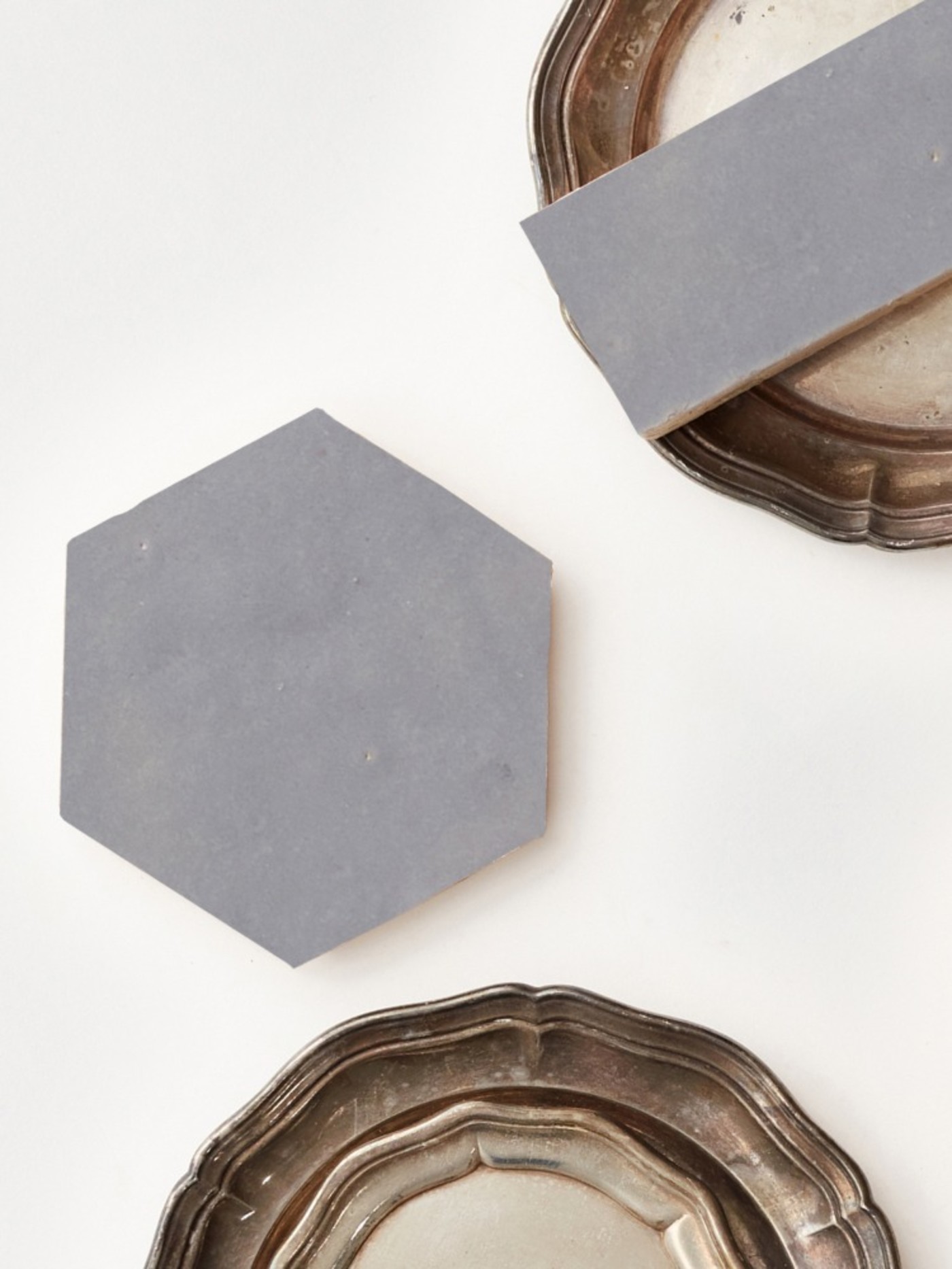 2 grey tiles on a set of silver plates on a white surface.