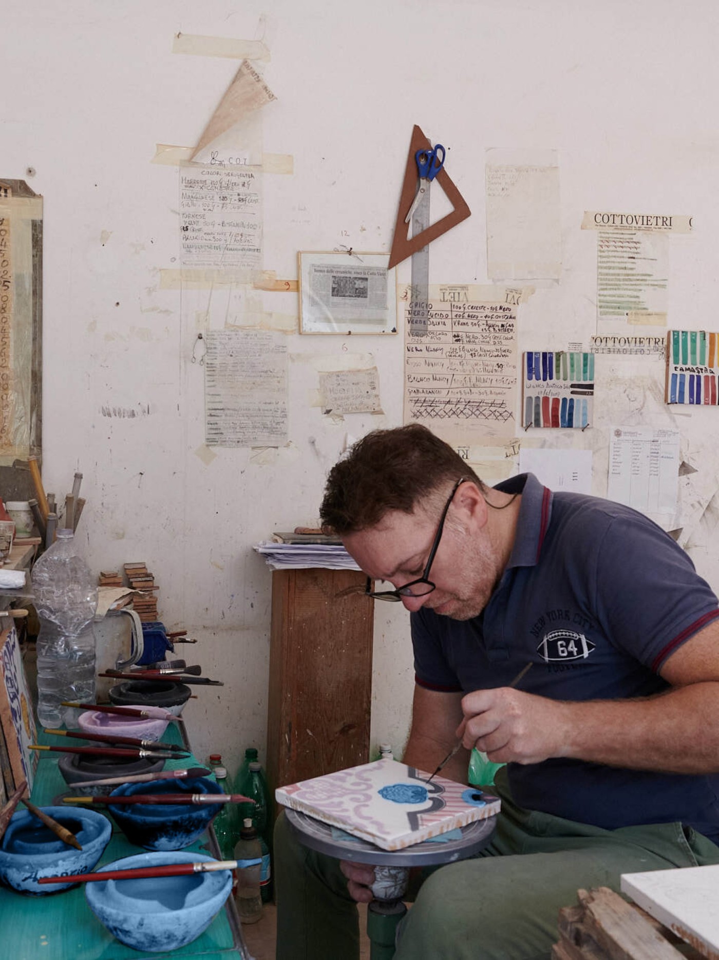 a man painting tile in an art studio.