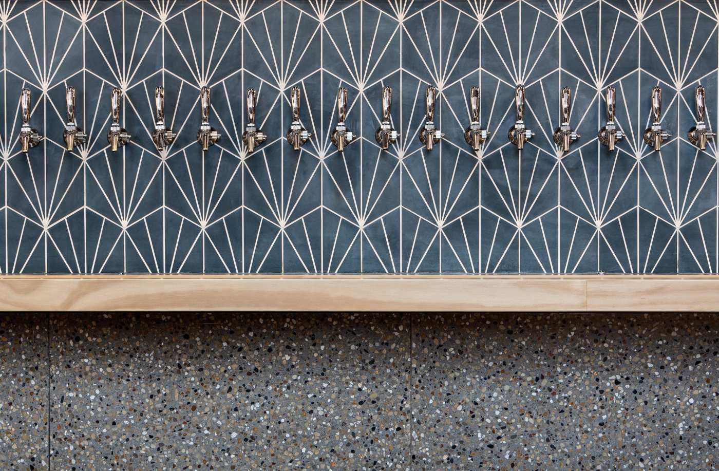 a blue tiled wall with beer taps on it.