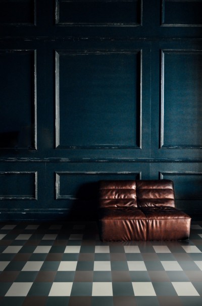 a brown leather couch in a room with a checkered floor.