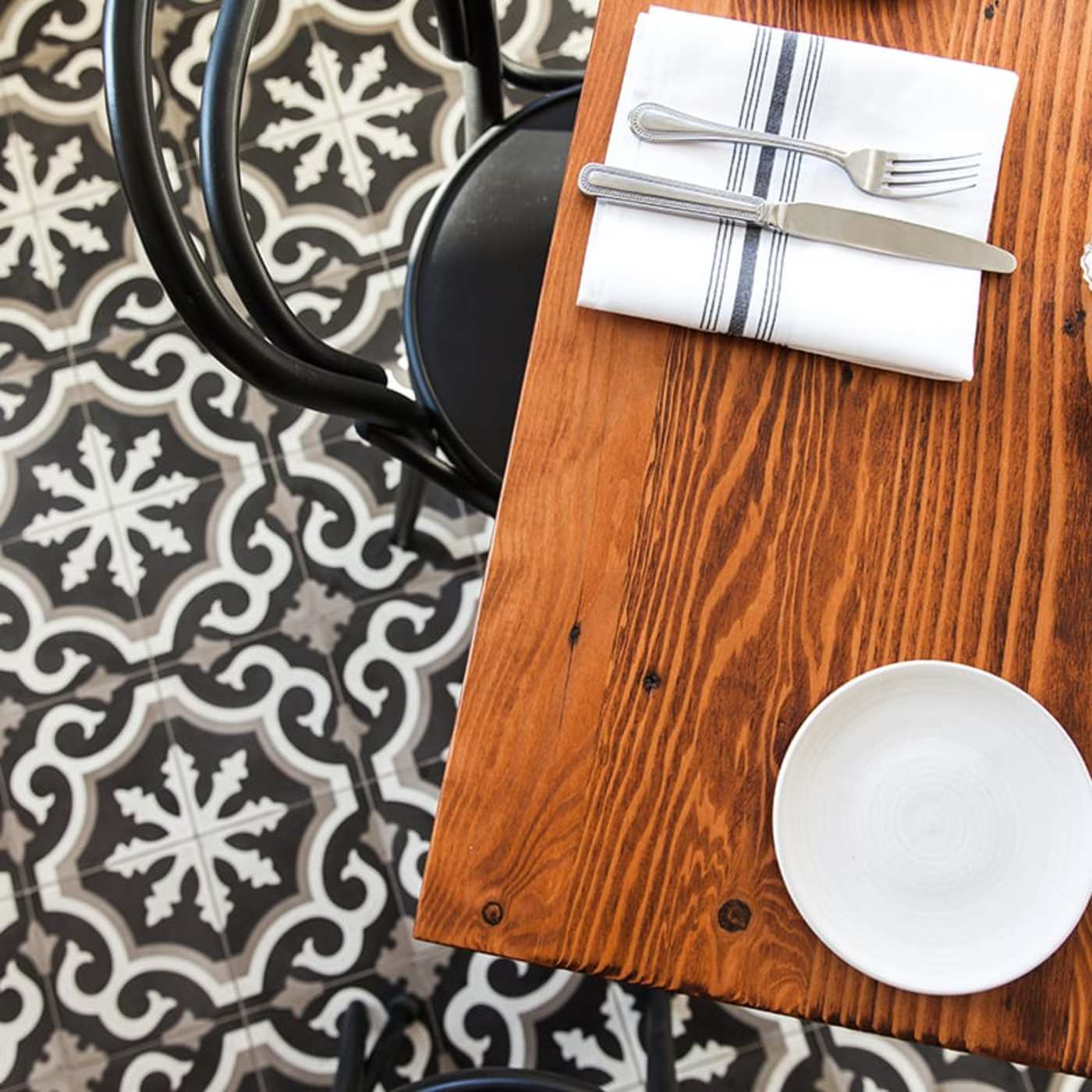 a table with plates and silverware on it above a black and white tiled floor.